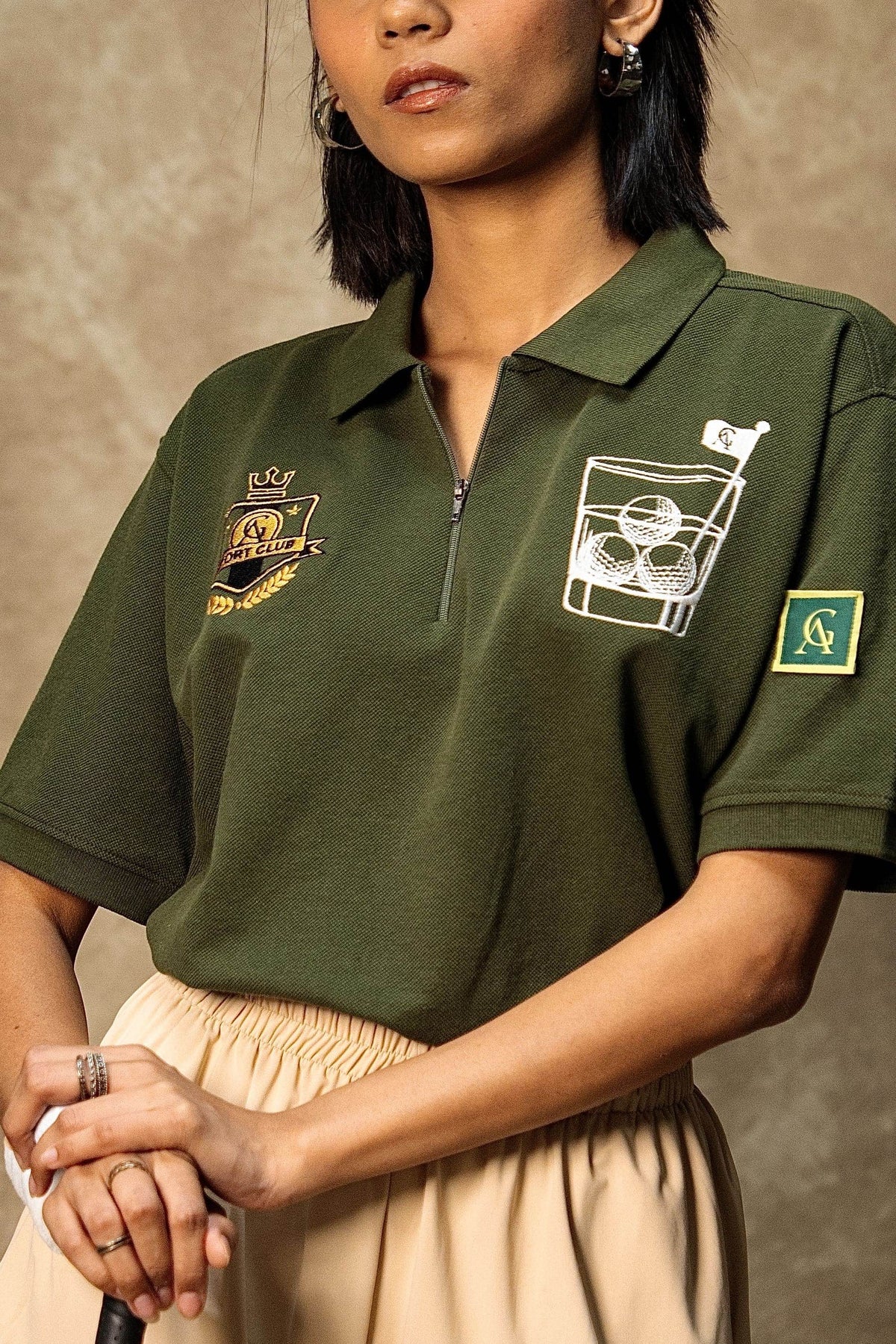 The 18th Hole Classic Polo (Unisex): model wearing the olive green polo, chest detail view