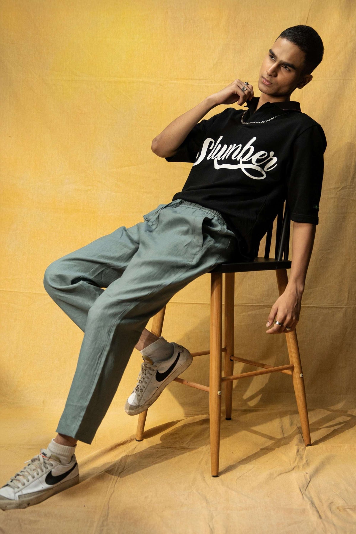 Slumber Lounge Polo (Unisex): model wearing the black polo, full-length seated view