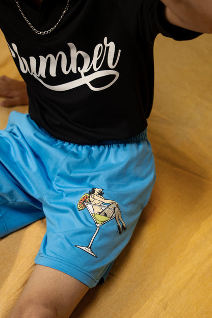 The Dirty Martini Lounge Shorts (Unisex): seated front view of the blue shorts on a model