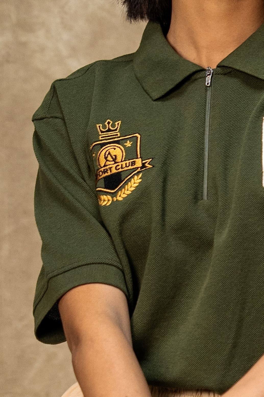The 18th Hole Classic Polo (Unisex): close-up of the quarter zip and gold sport club crest