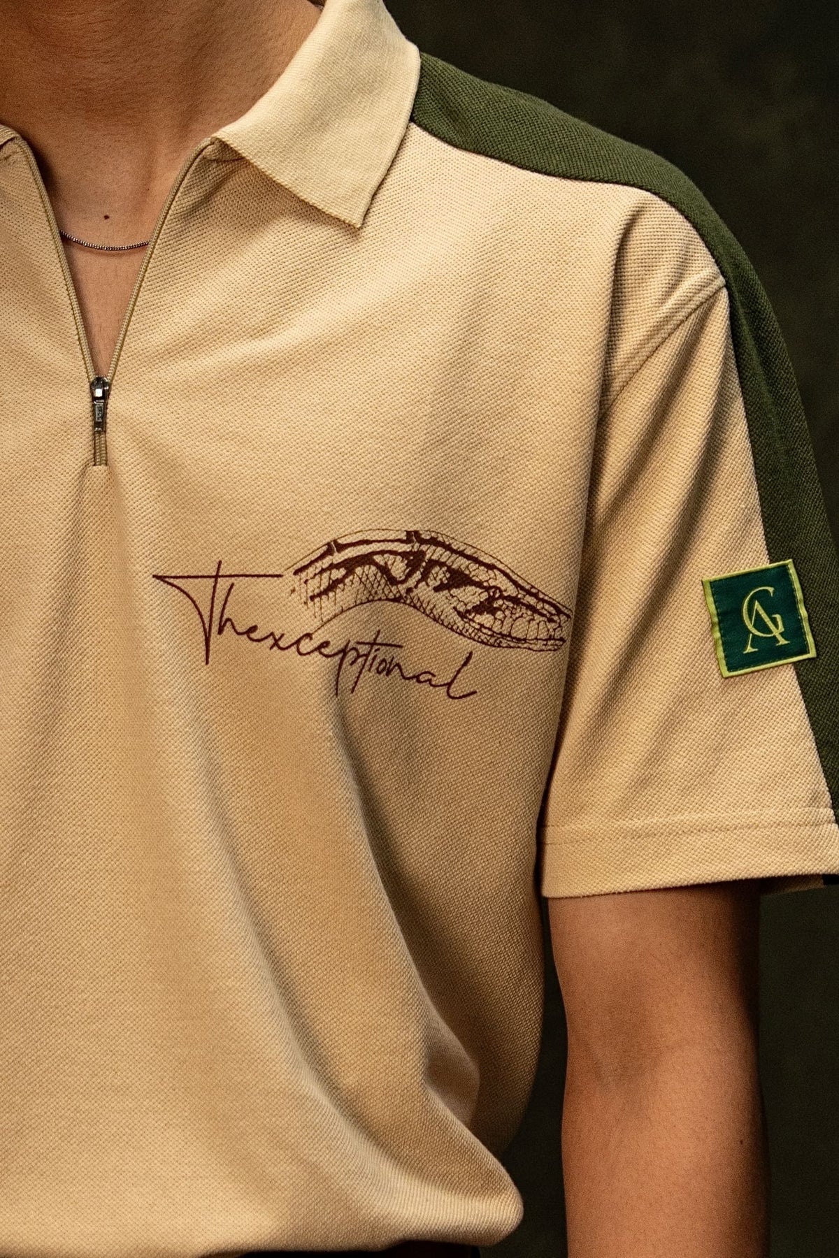Slither Classic Polo (Unisex): close-up of the quarter zip, chest lettering and sleeve patch