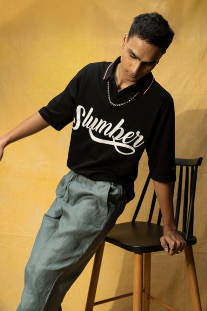 Slumber Lounge Polo (Unisex): model wearing the black polo leaning on a chair